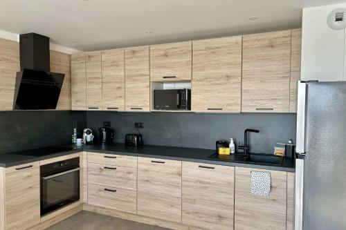 a kitchen with wooden cabinets and a black counter top at Air-conditioned Apartment with terrace in Illkirch-Graffenstaden