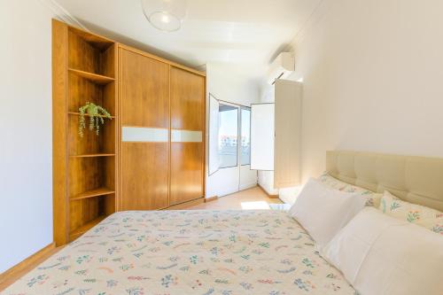 a bedroom with a bed and a wooden cabinet at Casa Vila-mar Porto Covo in Porto Covo