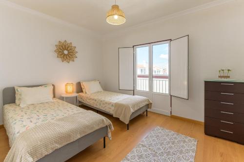 a bedroom with two beds and a dresser and a window at Casa Vila-mar Porto Covo in Porto Covo