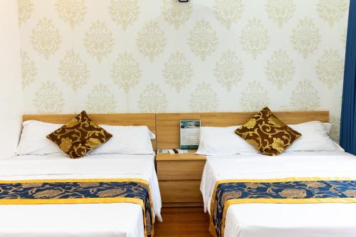 a hotel room with two beds and a wall at Nhà nghỉ Đức Trọng in Móng Cái