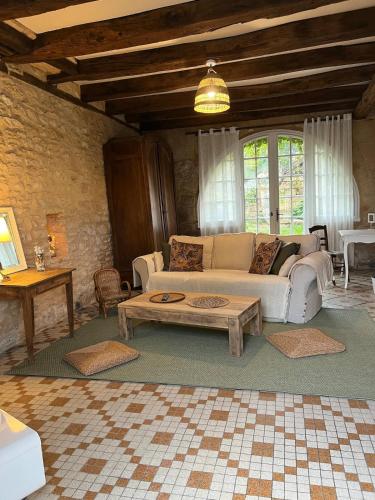 Una sala de estar con un sofá y una mesa de café. en Le chemin des écoliers 4 couchages, jardin, en Beynac-et-Cazenac