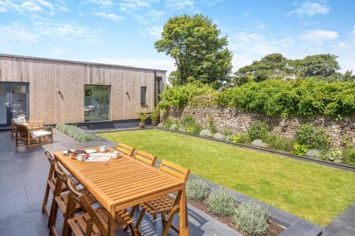 an outdoor patio with a wooden table and a lawn at Woodside Barn Hartland in Hartland