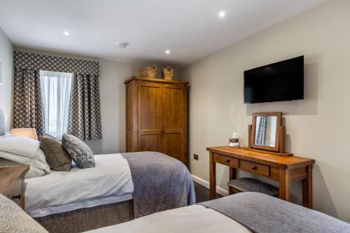 a bedroom with two beds and a desk and a television at Woodside Barn Hartland in Hartland