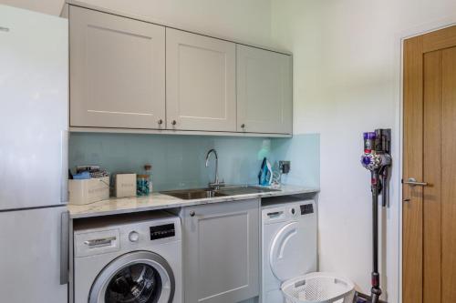 a kitchen with a washing machine and a sink at Woodside Barn Hartland in Hartland