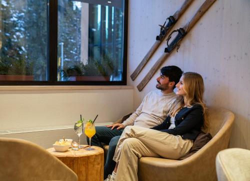 a man and a woman sitting on a couch at Ambiez Residencehotel in Madonna di Campiglio
