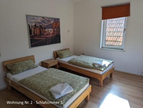zwei Betten in einem Zimmer mit einem Bild an der Wand in der Unterkunft Ferienwohnungen Schallenberg Nr 2 in Groß-Umstadt