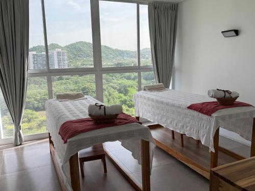 two beds in a room with a large window at Porto Horizonte Suite 1120 in Santa Marta