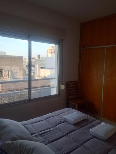 a bedroom with a bed and a large window at Dpto Zapiola - 2 Ambientes 3er piso por escalera in Bahía Blanca