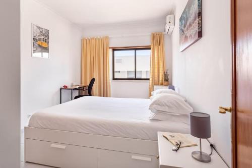 ein Schlafzimmer mit einem weißen Bett und einem Fenster in der Unterkunft GuestReady - Deluxe home with terrace in Caparica in Costa da Caparica