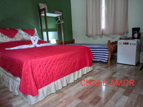 a bedroom with a red bed with a red blanket at Chalés Mimar Lumiar Suítes individuais in Lumiar