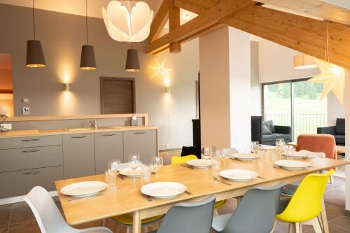 a dining room with a wooden table and yellow chairs at Le 240, entre lac et montagnes in Les Rousses