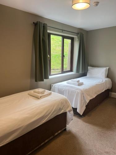 two beds in a room with a window at Bowood Park Hotel in Camelford