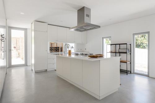 a white kitchen with white cabinets and a kitchen island at GuestReady - Exquisite villa w/ Pool & Parking in Pancas