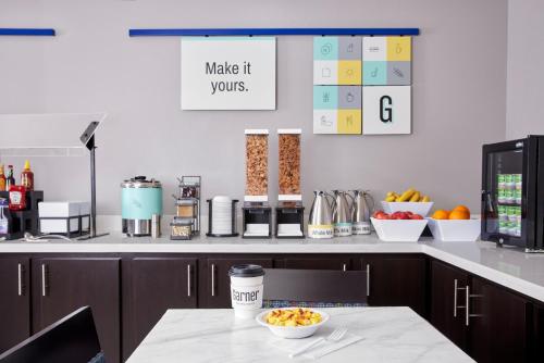 a kitchen with a counter with a bowl of fruit on a table at Garner Hotel Evansville East by IHG in Evansville