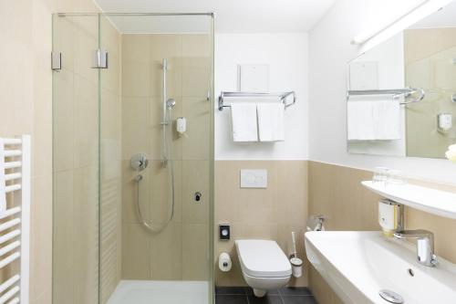 a bathroom with a shower and a toilet and a sink at Garner Hotel Frankfurt - Palmengarten by IHG in Frankfurt/Main