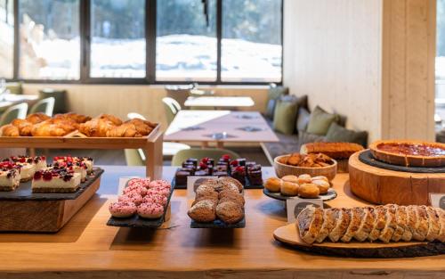 a table filled with different types of pastries and cakes at Ambiez Residencehotel in Madonna di Campiglio