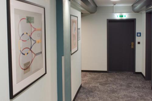 a hallway with paintings on the walls and a door at Garner Hotel Frankfurt - Palmengarten by IHG in Frankfurt/Main