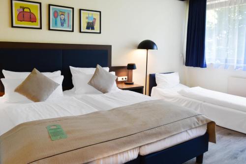 a hotel room with two beds and a window at Garner Hotel Frankfurt - Palmengarten by IHG in Frankfurt/Main