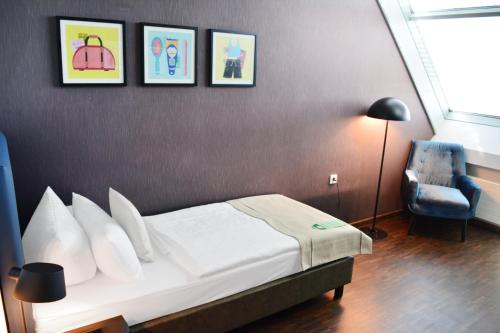 a hotel room with a bed and a chair at Garner Hotel Frankfurt - Palmengarten by IHG in Frankfurt/Main