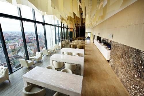 a restaurant with tables and chairs and large windows at The Manchester Deansgate Hotel, by IHG in Manchester