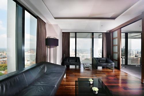 a living room with a leather couch and large windows at The Manchester Deansgate Hotel, by IHG in Manchester