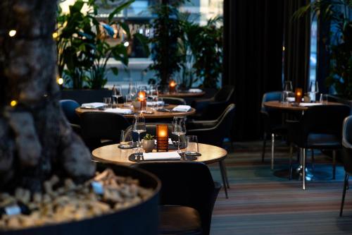 a row of tables in a restaurant with candles at The Manchester Deansgate Hotel, by IHG in Manchester