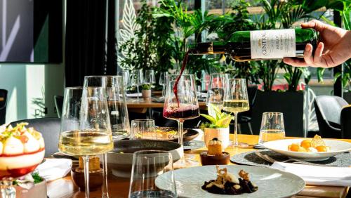 a person pouring a glass of wine on a table at The Manchester Deansgate Hotel, by IHG in Manchester