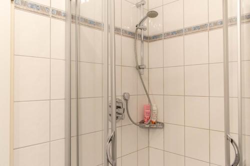a shower in a white tiled bathroom at Ferienwohnung Seestern in Timmendorfer Strand