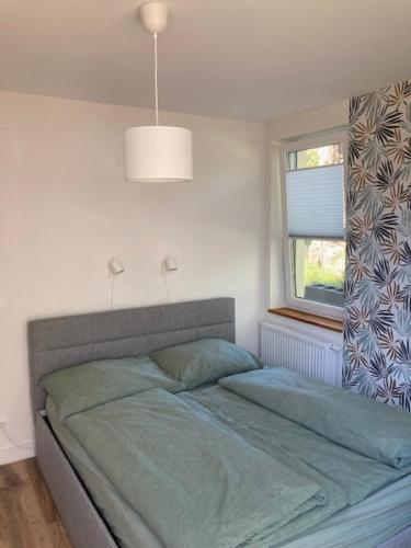 Una cama en un dormitorio con una ventana y una lámpara. en Seaside Apartment, en Trzęsacz