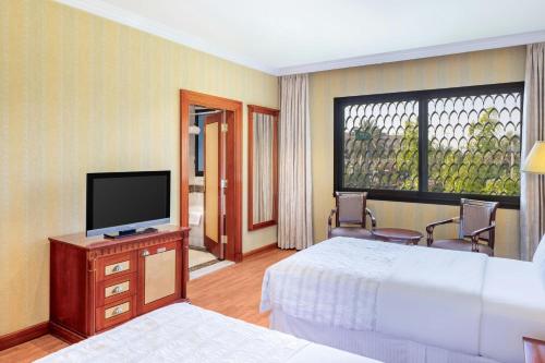a hotel room with a bed and a television at Le Meridien Medina in Al Madinah