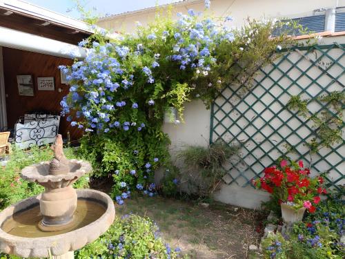 a garden with a fountain and blue flowers at Chambre d'hote Jasse Perdrix in Thairé