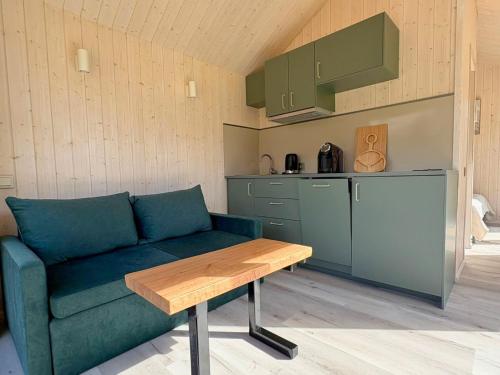 un salon avec un canapé bleu et une table dans l'établissement Rātes Krasti - PĒRLE- holiday house with sauna and lakeview, à Lejasciems