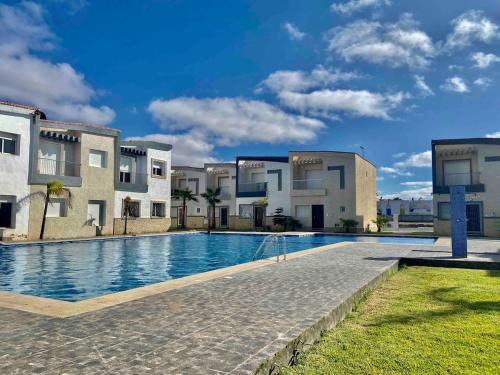 a large swimming pool in front of some buildings at Ocean View Villa avec Piscine en Bord de Mer in Sidi Rahal