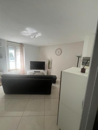 a living room with a black couch and a television at T2 apartment, terrasse cours intérieur in Narbonne