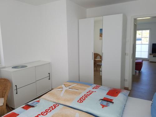 a white room with a bed and a dresser at Ferienwohnung Schatzkästchen in Dranske