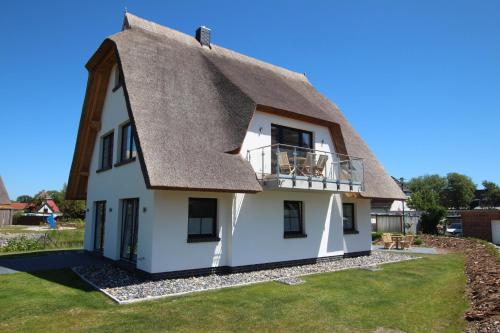 a thatched roof house with a balcony at Ferienwohnung Schatzkästchen in Dranske