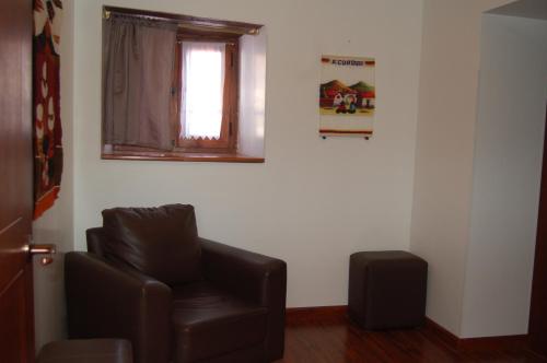 a living room with a leather chair and a window at Hotel El Molino Alausí in Alausí