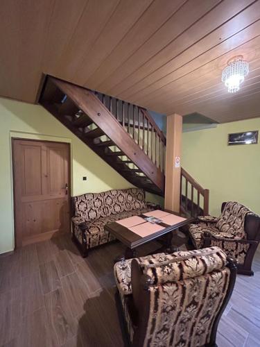 a living room with couches and a table and stairs at Párty penzion Dolany in Čkyně