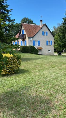 una grande casa bianca con finestre blu e un cortile di Le Châtelier a Saint-Benoît-la-Forêt
