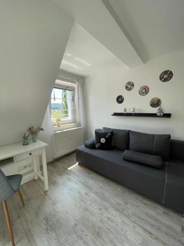 a living room with a black couch and a window at Ferienwohnung Maria mit Elbblick in Coswig