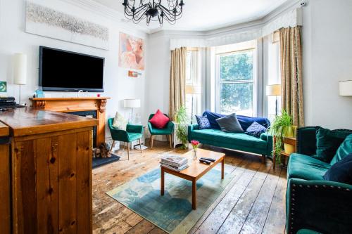 a living room with green furniture and a flat screen tv at OYO The Lodge Bournemouth in Bournemouth