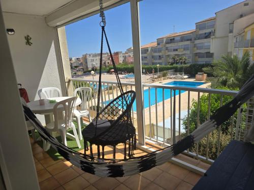a hammock on a balcony with a view of a pool at Apartment with pool included in Agde