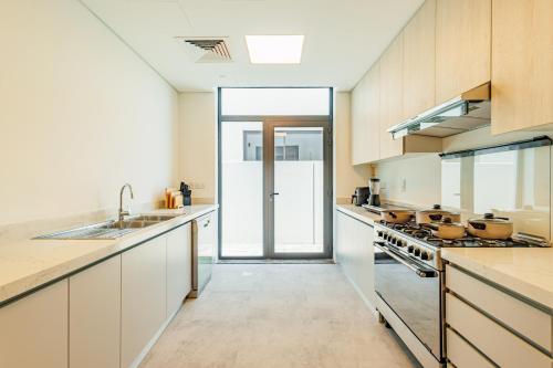 a large kitchen with white cabinets and a glass door at Luxurious Villa on Saadiyat for Large Groups and Families in Abu Dhabi