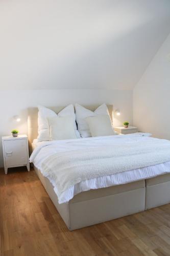 una cama blanca con sábanas y almohadas blancas en Naemi Premium Apartment Hannover, en Langenhagen