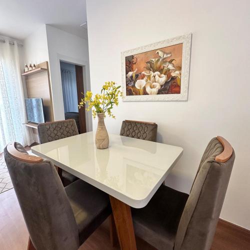 a white dining room table with chairs and a vase with flowers at Plano 22 Prime Loft in Extrema