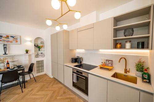 a kitchen with white cabinets and a sink and a table at Beach Getaway in Eastbourne