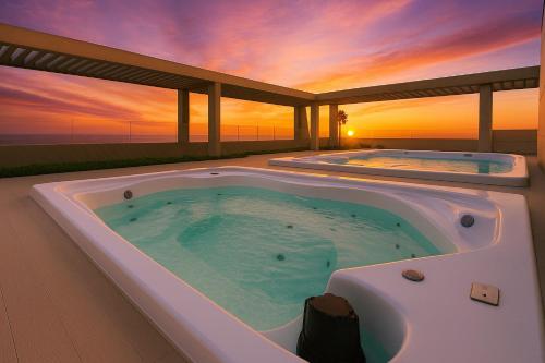a jacuzzi tub with a sunset in the background at Distrito 90 luxury suites in Barranquilla