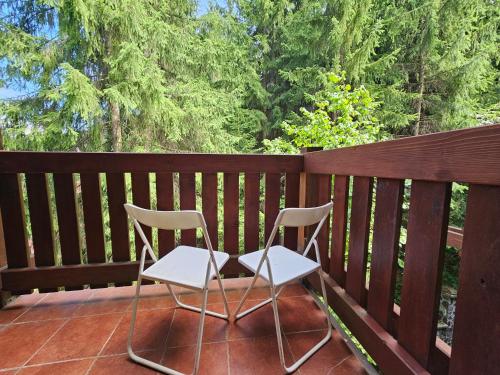 two chairs sitting on a deck with trees in the background at Fatrapark 1 Apartments in Ružomberok