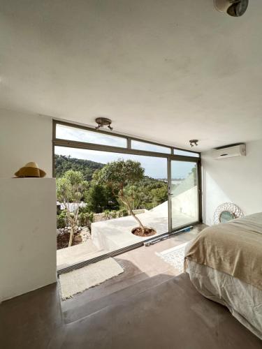 a bedroom with a bed and a large window at Villa Entre ciel et sel in Ses Salines