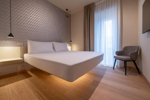 a bedroom with a large white bed and a chair at Oriana Homèl Milano in Milan